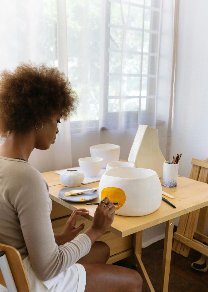 Woman painting ceramics in a bright studio, highlighting creativity and craftsmanship