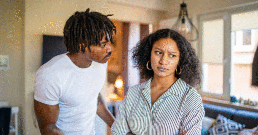 Black woman with arms crossed showing firm boundaries while man tries to explain during relationship disagreement