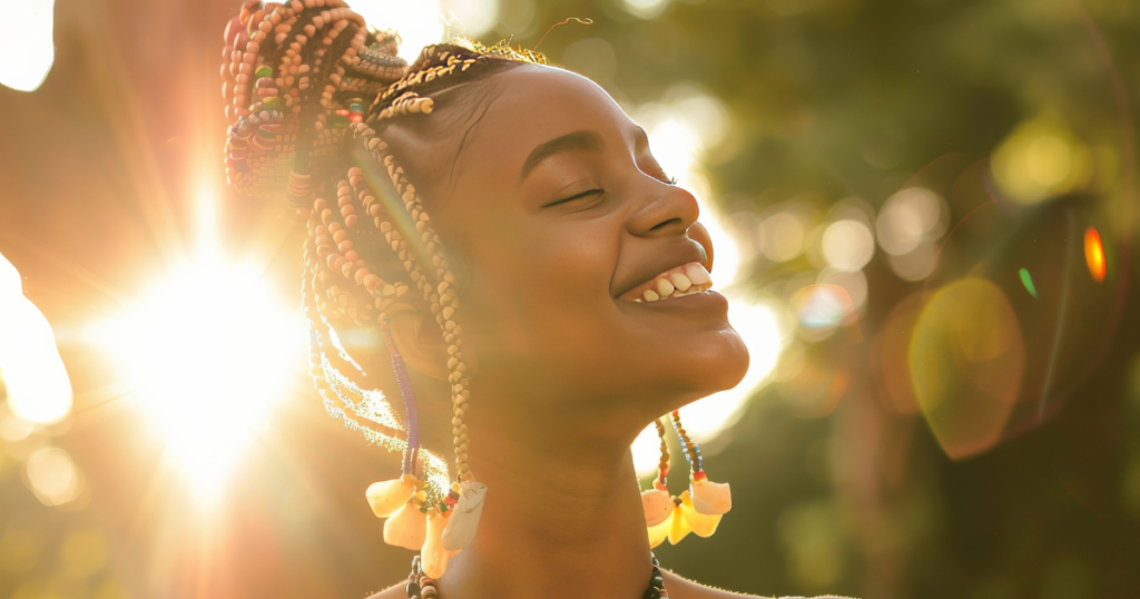 “Smiling young Black woman with braided hair glowing in warm sunlight, embodying confidence, joy, and personal growth—reflecting self-improvement and empowerment for Black women.”